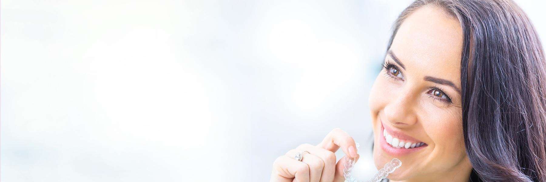 woman holding invisalign braces in GA